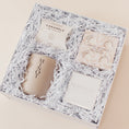 Load image into Gallery viewer, Lavender and Pine Refined Escape Gift Box angle view featuring McCrea's Cape Cod sea salt caramels, Thulisa Naturals shower steamer discovery set, Minot Cliffwalk candle, and Shinery radiance towelettes in white luxe two piece gift box