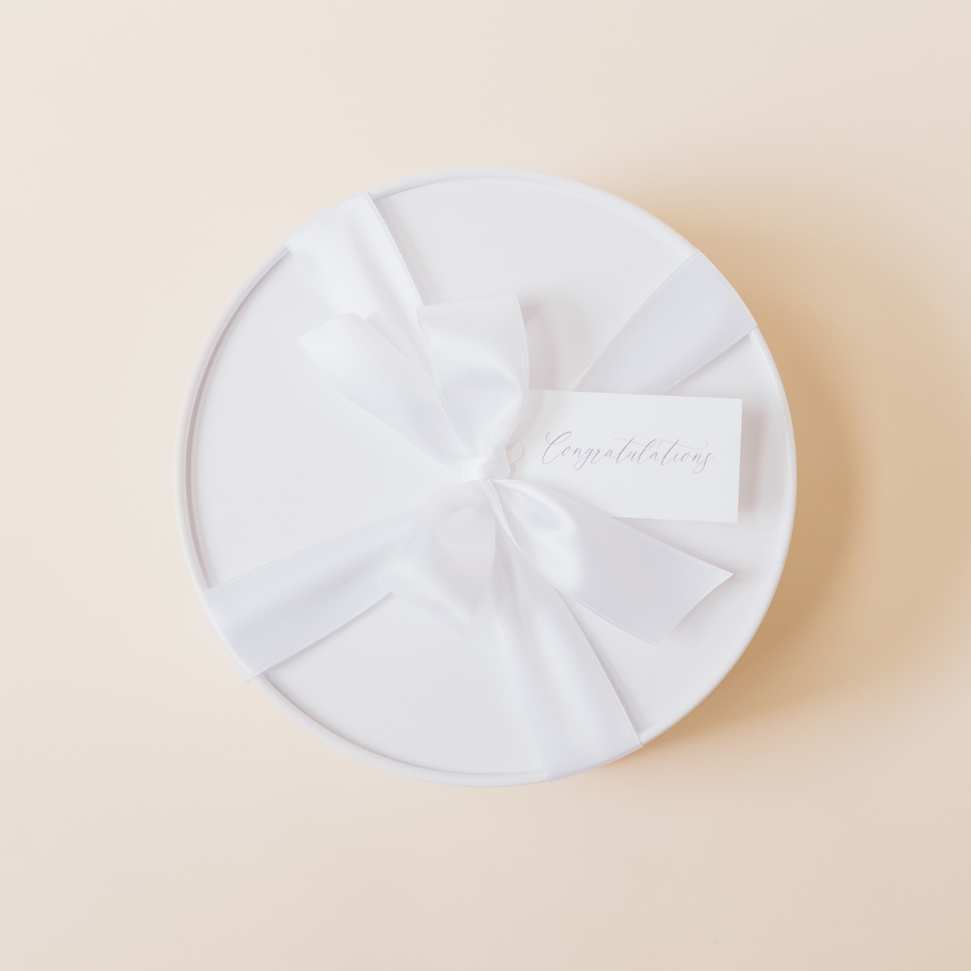 White round gift box with satin ribbon and congratulations tag – curated luxury gift packaging by Lavender + Pine