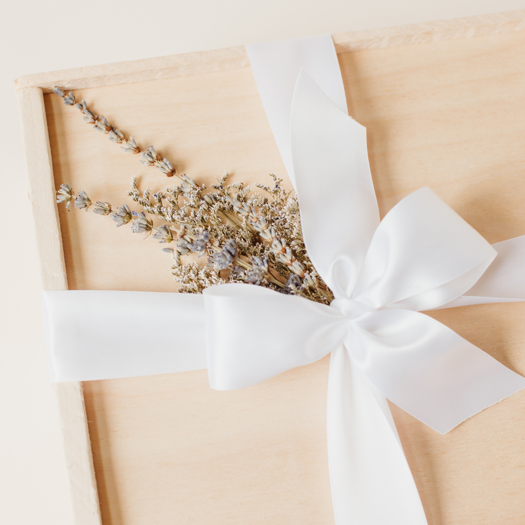 Elegant wooden gift box tied with a white satin ribbon and adorned with dried lavender and florals - Lavender + Pine referral gifting