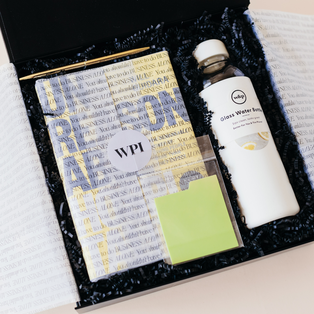 Custom gift box featuring the Unreasonable Hospitality book wrapped in branded tissue paper, a glass water bottle, sticky notes, and a gold pen, curated by Lavender and Pine.