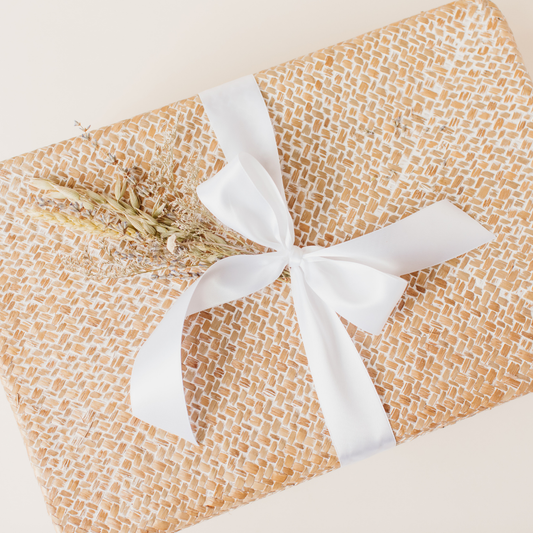 Woven gift box with white satin ribbon and dried floral bundle, styled by Lavender + Pine for a women-owned business feature.