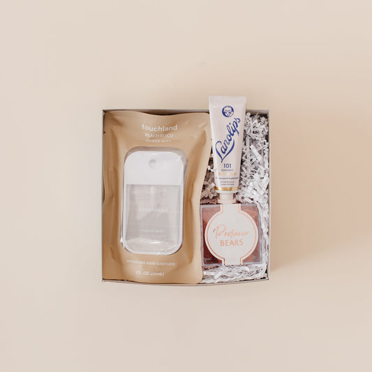 Lavender and Pine Glow and Go Gift Box featuring Touchland Beach Coco Power Mist, Lanolips 101 ointment, and Prosecco Bears in mini tuck top gift box