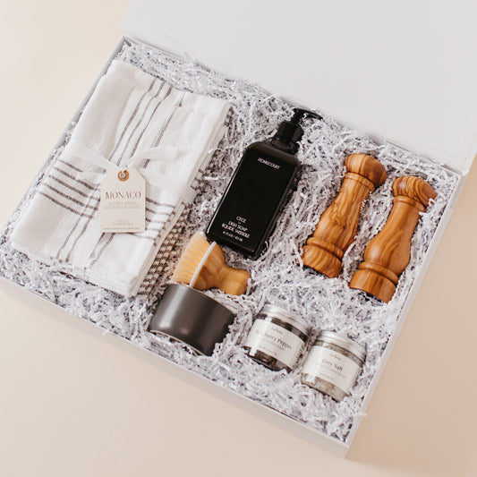 Lavender and Pine Kitchen Essentials Gift Box angle view featuring Monaco kitchen towels, Homecourt Cece dish soap, dish brush set, Natural OliveWood salt and pepper mills, and La Boite Tellicherry pepper and grey salt in white magnetic gift box