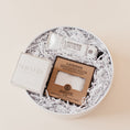 Load image into Gallery viewer, Lavender and Pine Love at First Site Gift Box overhead angle featuring ElizabethW lavender shea butter hand cream, ElizabethW lavender exfoliating shower pouch, and Shinery radiance towelettes in white round gift box
