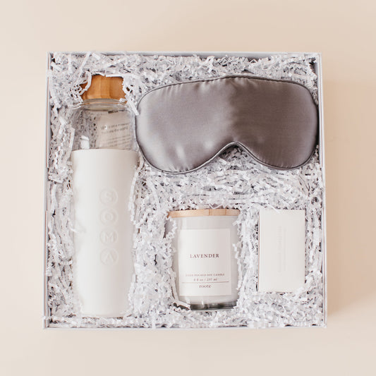Lavender and Pine Rest and Restore Gift Box featuring Soma glass water bottle, Pure Sol silk sleep mask, Roote lavender candle, and Shinery radiance towelettes in white luxe two piece gift box