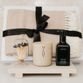 Load image into Gallery viewer, Lavender and Pine Sanctuary Gift Box close up view featuring Minot candle, Homecourt Neroli Leaf hand wash, black tip apothecary matches, Fennco Styles throw blanket, and Luxe B Co sandstone trivet riser in white magnetic gift box
