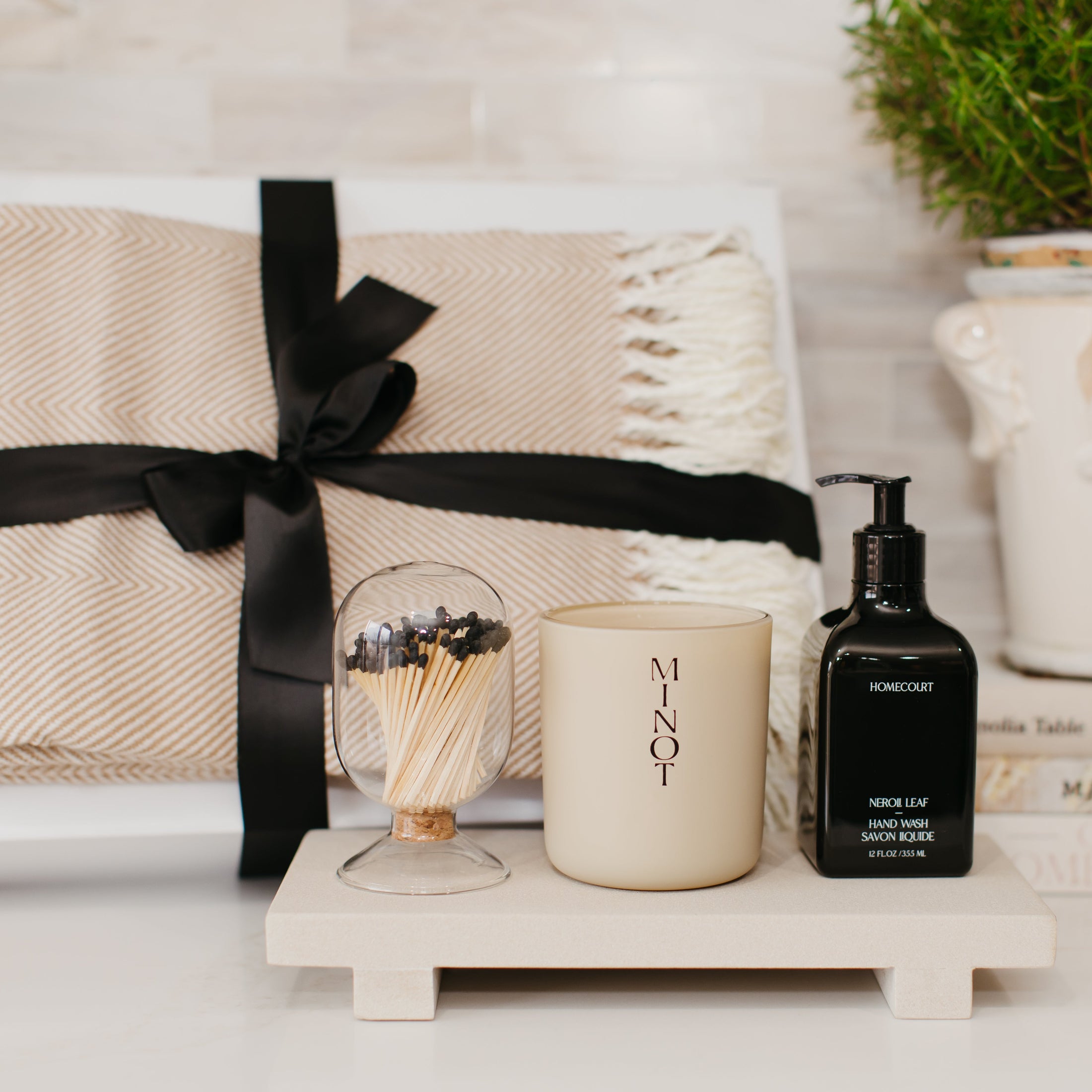 Lavender and Pine Sanctuary Gift Box styled view featuring Minot candle, Homecourt Neroli Leaf hand wash, black tip apothecary matches, Fennco Styles throw blanket, and Luxe B Co sandstone trivet riser in white magnetic gift box