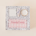 Load image into Gallery viewer, Lavender and Pine Sweet Surprise Gift Box featuring Scandy Candy Swedish candy, Shinery radiance towelettes, Lanolips 101 ointment, and Apricity Ceramics gold rim ring dish in white luxe two piece gift box
