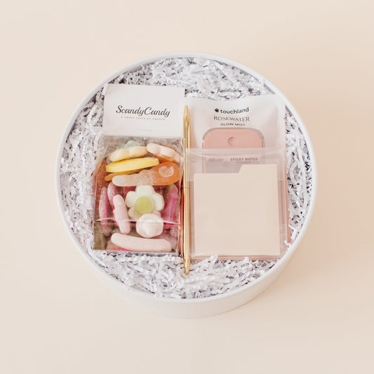 Lavender and Pine Desktop Edit gift box featuring Scandy Candy Swedish candy, Touchland Rosewater Glow Mist, gold pen, and cream tabbed sticky notes in white round gift box