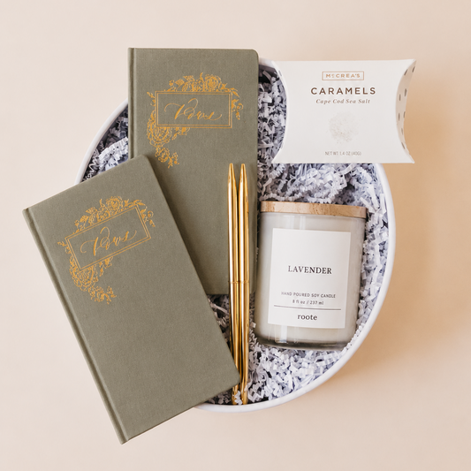 Lavender and Pine Written in Love Gift Box angle view featuring Seniman Calligraphy olive vow books, gold ballpoint pens, Roote lavender candle, and McCrea's Cape Cod sea salt caramels in white round gift box